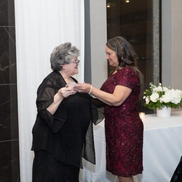 Two woman dressed up at an event talking.